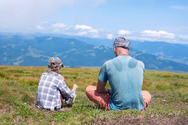 Vader en zoon rusten samen op de alpine meadow — Stockfoto