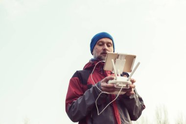 Sakallı adam uzaktan kumanda elinde tutar. 