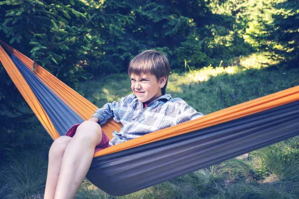 Boy is swinging in a hammock, with funny face — Stock Photo, Image