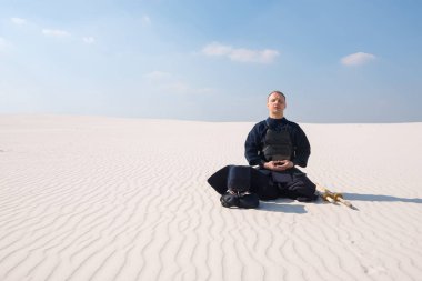 Man in traditional armor for kendo meditates before the practice clipart