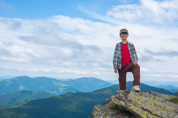 Sorrindo menino fica no penhasco na montanha — Fotografia de Stock