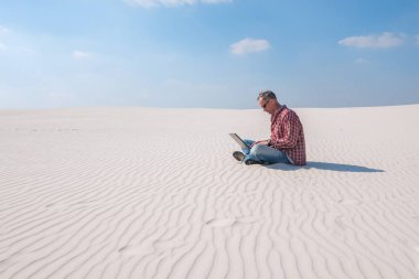 İş hakkında tutkulu biri a laptop ile çölde oturur