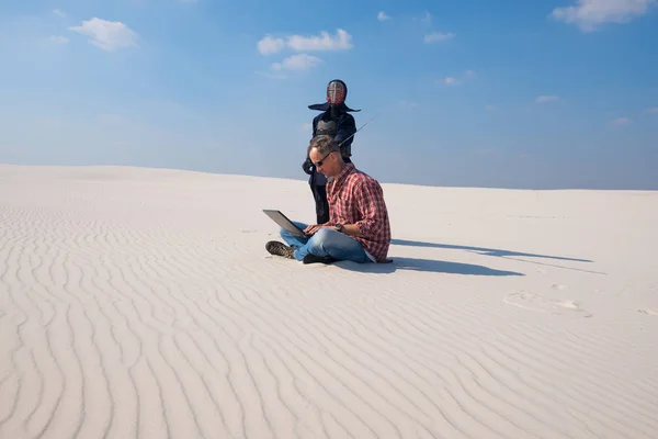 Człowiek w stres, siedzi z laptopa w środku pustyni — Zdjęcie stockowe