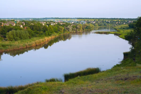 Kalme rivier stroomt door een dorp in het midden van een groene prai — Stockfoto