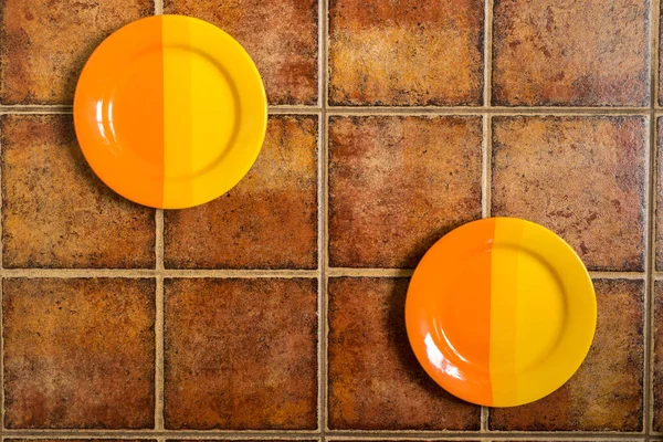 Two multi-colored plates located in different corners on a brown — Stock Photo, Image