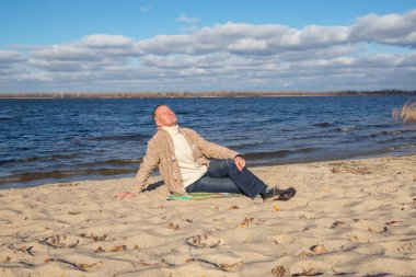 Adam nehir kıyısında oturuyor ve hayatın tadını çıkarıyor