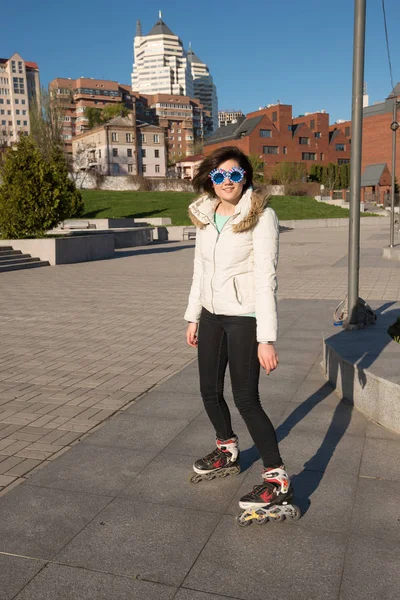 Souriante fille dans un drôle de patinage à roulettes de lunettes de soleil et posant dans — Photo