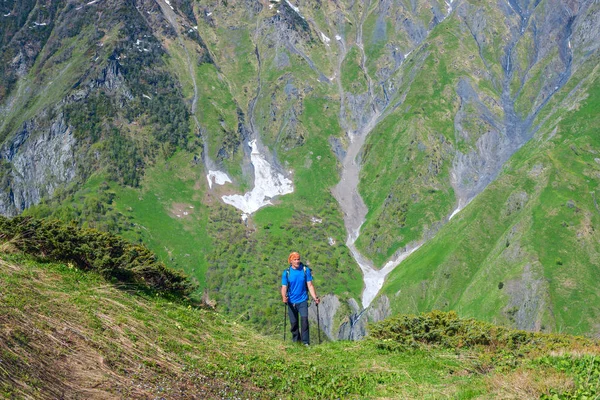 Reisender steigt den grünen Hang hinauf, in eine Bergschlucht — Stockfoto