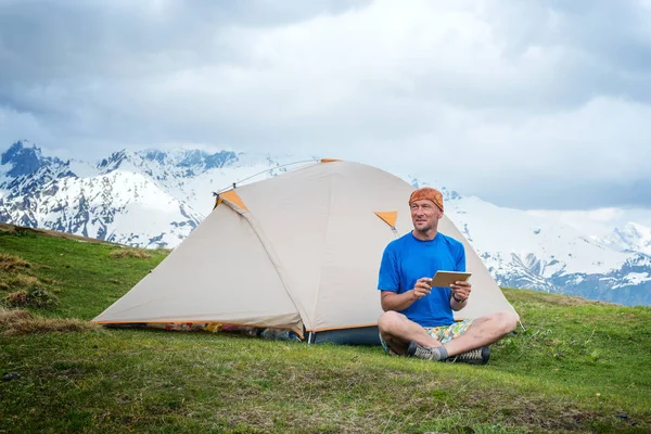 Смолянин сидит рядом с палаткой, в горах с помощью — стоковое фото