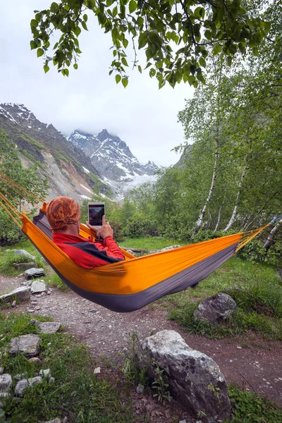 Aventurero relajándose en hamaca en las montañas, toma una foto u — Foto de Stock