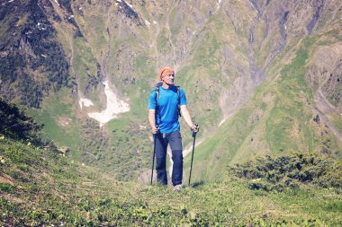 Memnun gezgin bir dağ gorge içinde yeşil yamaç tırmanıyor