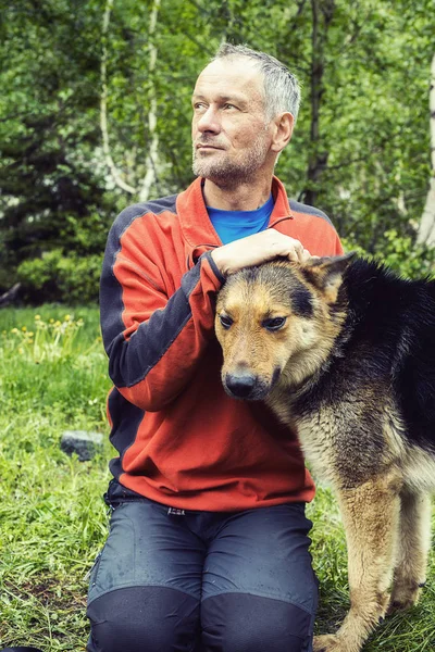 Man adventurer with big dog is resting in the forest — Stock Photo, Image