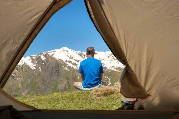 Человек-путешественник сидит на краю пропасти, любуясь заснеженной горой — стоковое фото