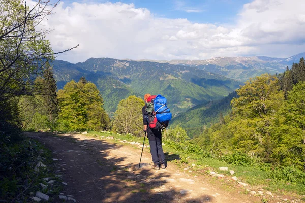 Homem viajante com mochila grande na estrada da montanha — Fotografia de Stock