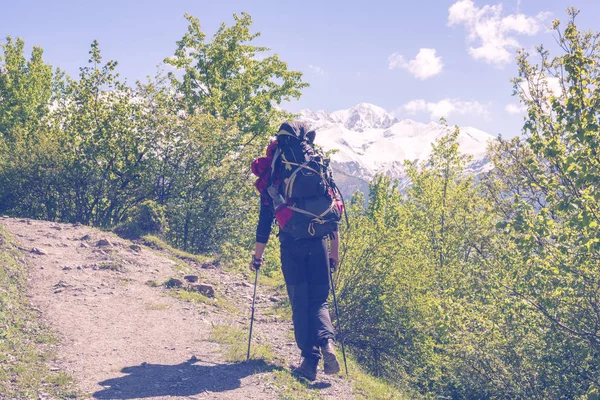 Reiziger met grote rugzak is zwaar langs een berg klimmen — Stockfoto