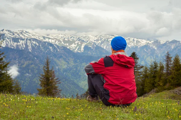 Мечтающий путешественник сидит на альпийском лугу — стоковое фото