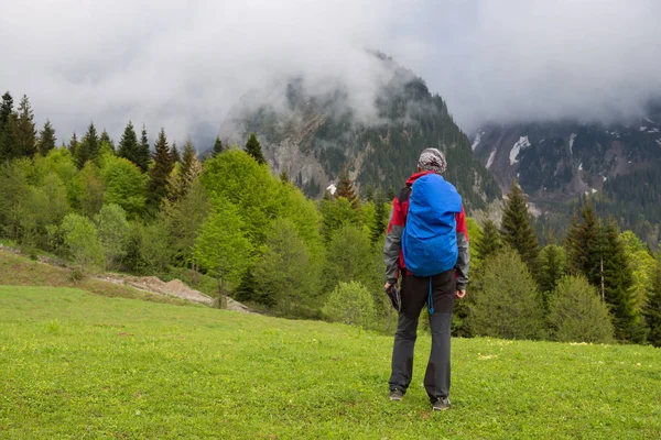 Man reiziger is wandelingen langs alpine meadow na storm — Stockfoto