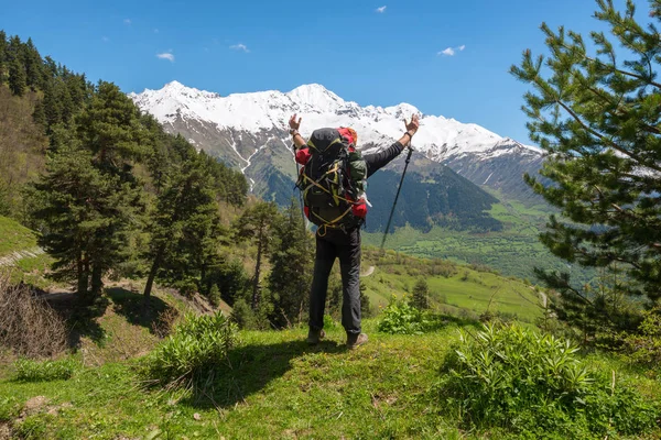 Vrolijke man reiziger met open armen staat op de alpine meadow — Stockfoto