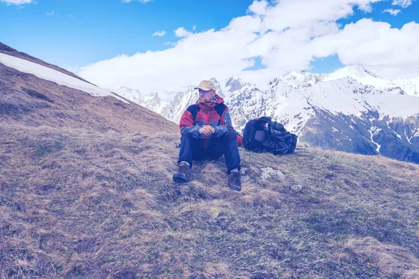 Cansado aventureiro descansa, sentado ao lado da mochila no mountai — Fotografia de Stock