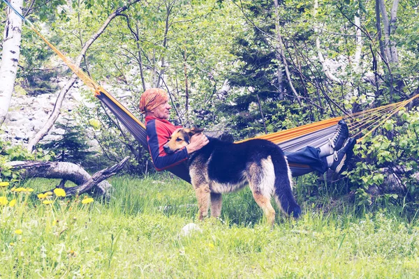 Adam Gezgin hamakta rahatlatıcı ve onun köpekle oynamayı