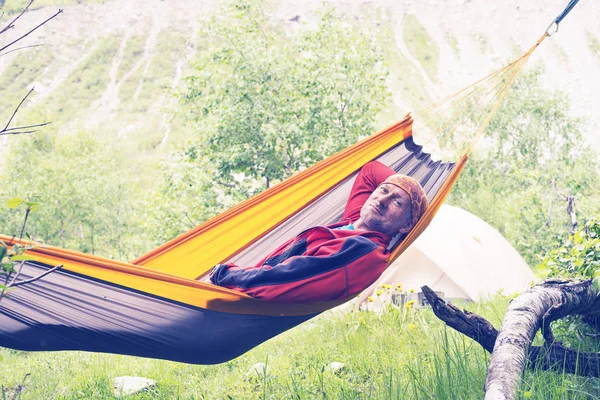 Feliz excursionista se relaja en hamaca en el prado alpino — Foto de Stock