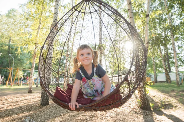 Küçük kız bir asılı sandalyede oynuyor