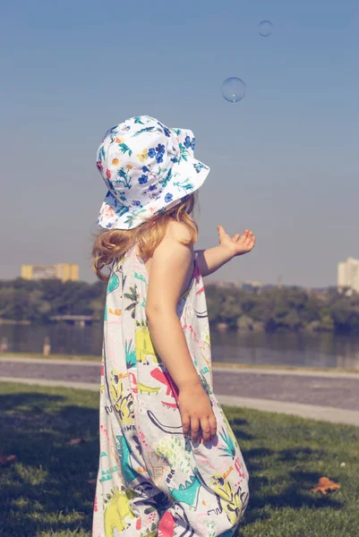 Küçük kız ellerini baloncuklar uzanır