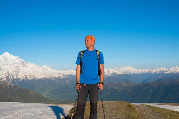 Glimlachende man reiziger is permanent op de bergweg — Stockfoto