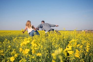 Neşeli çift sarı çiçek tarlasında eğleniyor