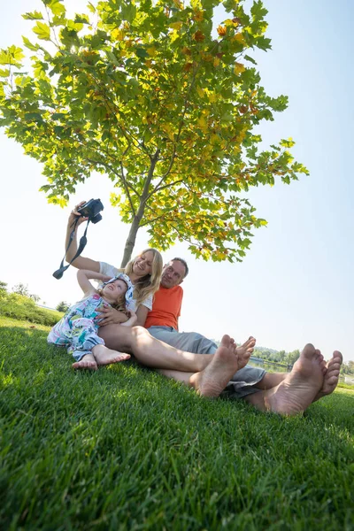 Joyful family taking selfie on a green meadow