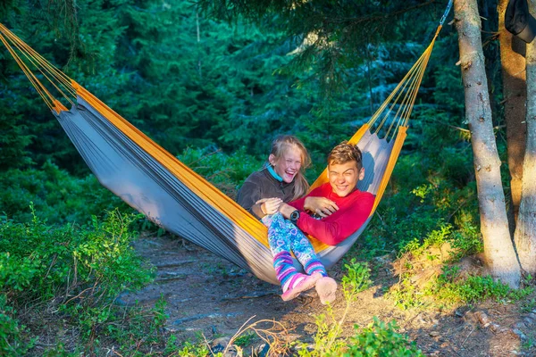 Joyful teenagers - brother and sister ride in a hammock — Stock Photo, Image