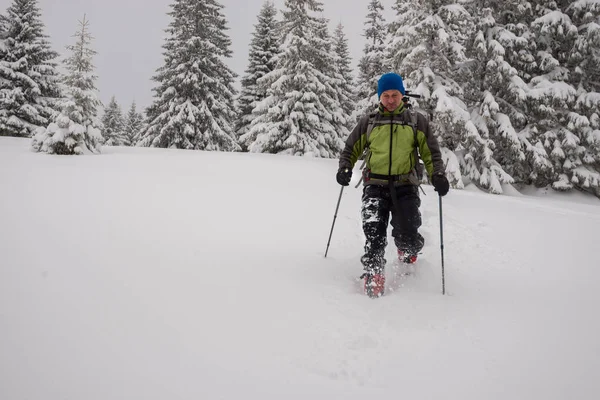 Hombre aventurero va raquetas de nieve en nieve profunda —  Fotos de Stock