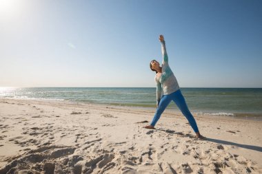 Kadın sahil üzerinde yoga uygulamak 