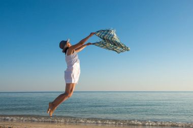 Beyaz giysili bir neşeli kadına bir ıssız plajda atlıyor