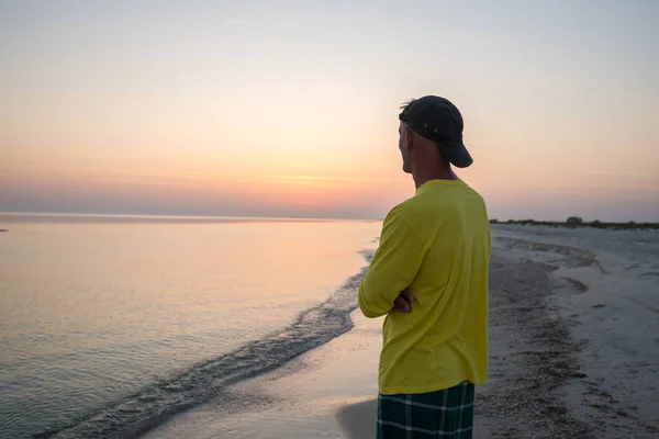 Hombre viajero está de pie solo en una línea de surf y admirando el sol — Foto de Stock