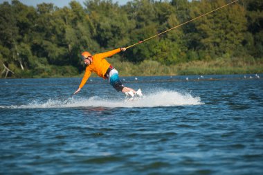 Wakeboarder, turuncu gömlek içinde el ile su sprey döner
