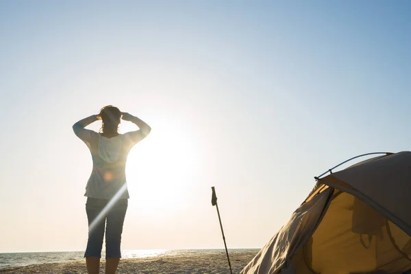 Женщина-путешественница, стоящая у палатки на берегу моря — стоковое фото