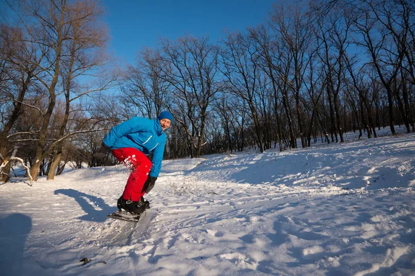 Un homme heureux au drôle de visage fait du snowboard dans les bois — Photo