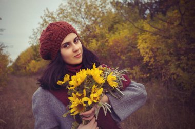 Gülümseyen kız sonbahar ormandaki bir bere içinde