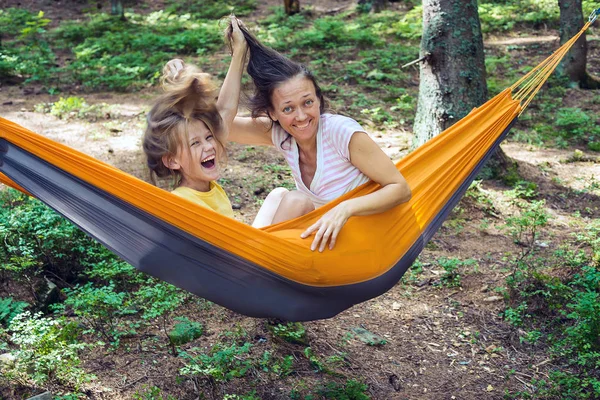 Joyful mom and daughter relax in a hammock — Stock Photo, Image