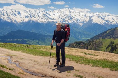 Gezgin büyük sırt çantası ile dağ yolunda duruyor 