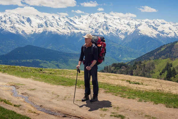 Gezgin büyük sırt çantası ile dağ yolunda duruyor 