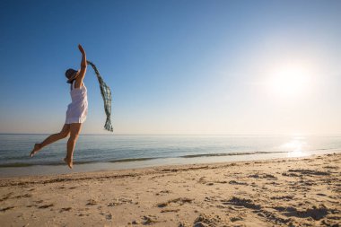 Sahilde bir eşarp ile neşeli kadın atlar