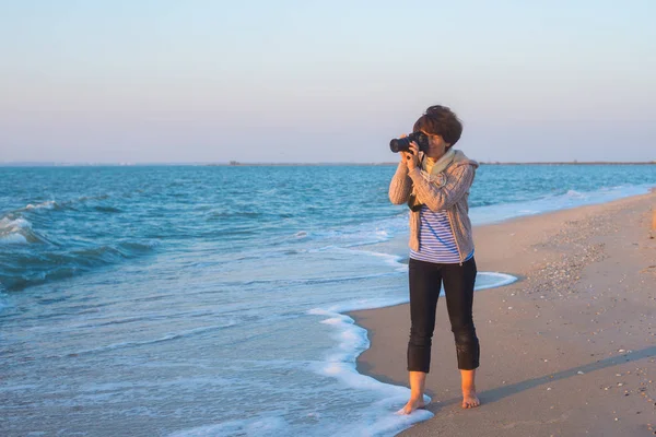 Kobieta fotograf robi zdjęcie na brzegu morza — Zdjęcie stockowe
