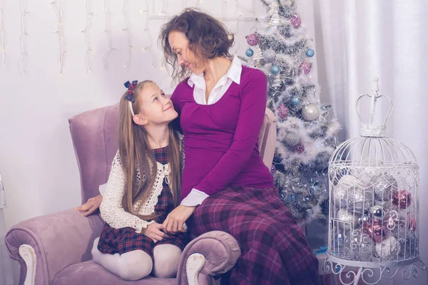 Mãe e filha felizes estão sentados na frente de uma árvore de Natal — Fotografia de Stock