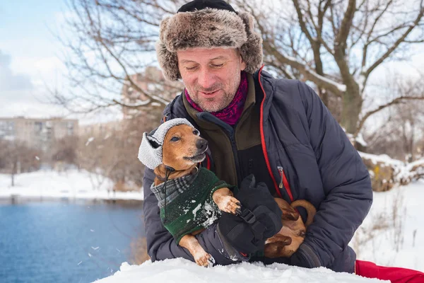 Glimlachende man en kleine hond, dragen in een grappige winter hoeden — Stockfoto