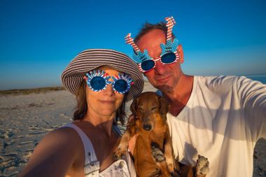 Komik çift, küçük bir köpekle se alarak karnaval güneş gözlüğü