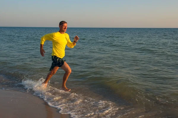 Viajero feliz, encantado, corre a lo largo de la línea de surf — Foto de Stock