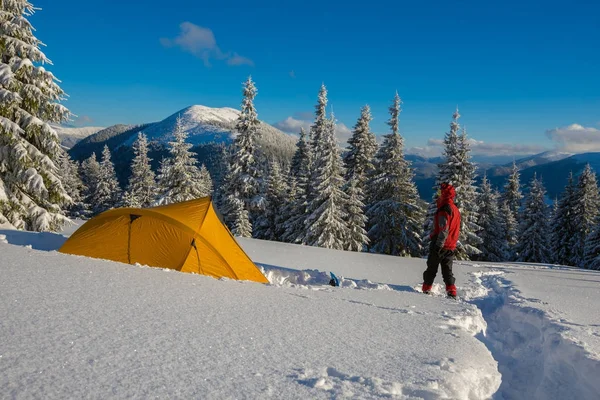 Adventurer stands in a deep snow near a yellow tent — Stock Photo, Image