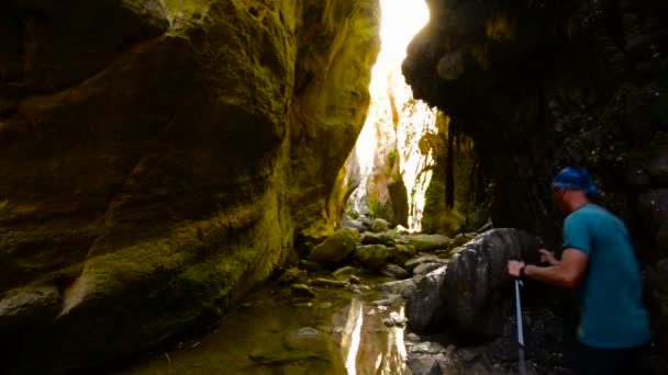 旅行者沿着峡谷 Avakas 从石头跳到石头 在一个晴朗的日子 可怕的冒险在塞浦路斯 背光源 后视图 — 图库视频影像